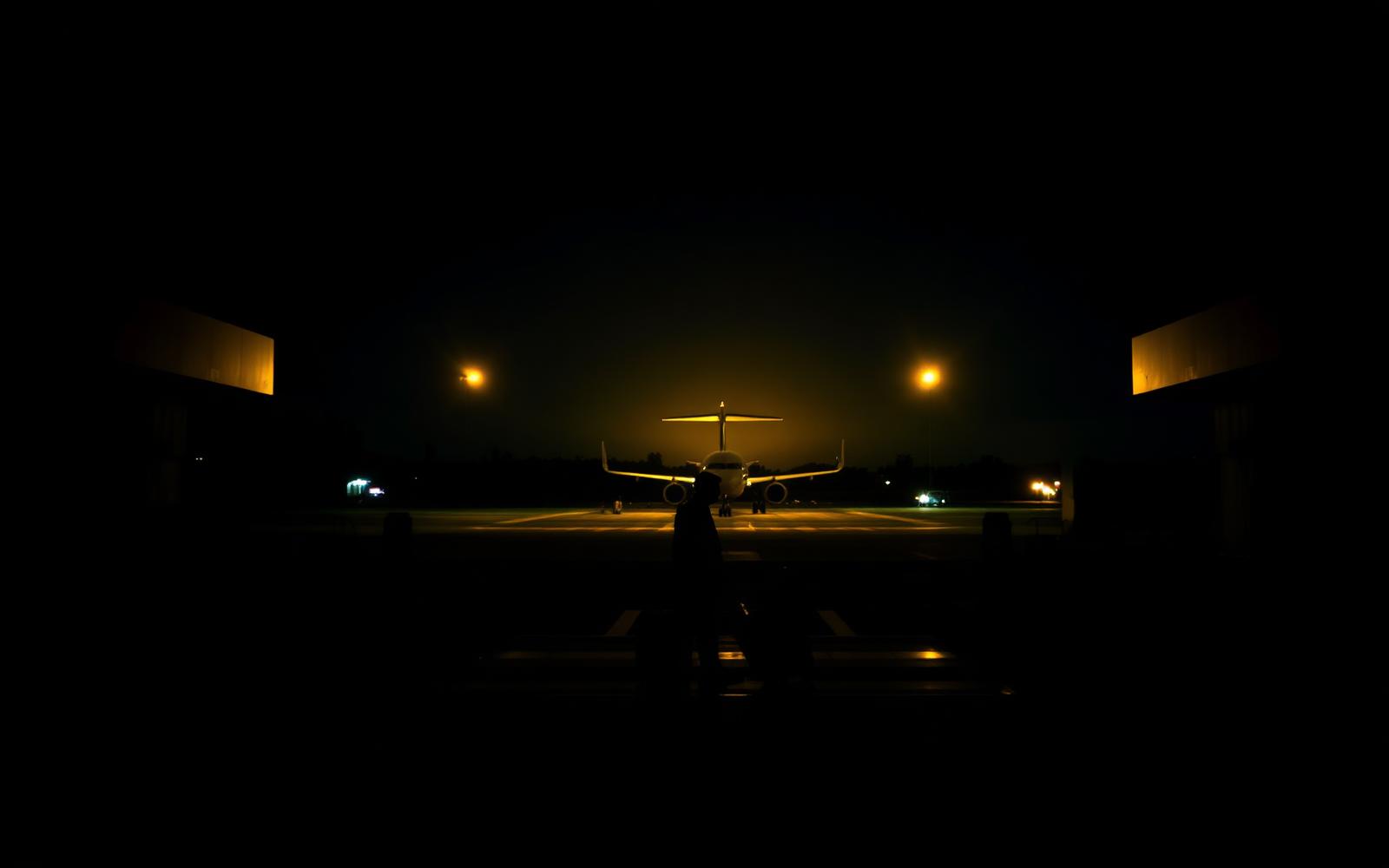 Traveler walking toward an aircraft on a night airport apron